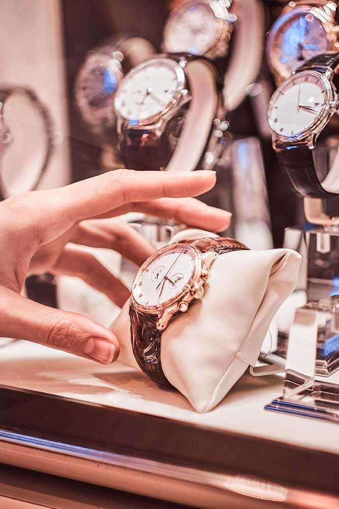 Nahaufnahme der Hand des Verkäufers zeigt die exklusive Herrenuhr aus der neuen Kollektion im Luxusjuweliergeschäft